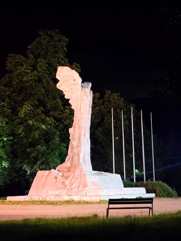 Late-night central Warsaw: wet streets, monuments, and city traffic