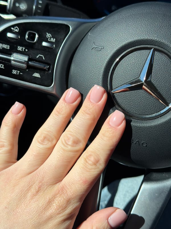 Woman's manicured hand captured on Mercedes steering wheel in Riga