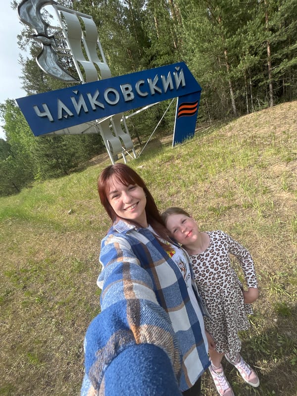 Two people rest by Chaykovsky city sign in Russia