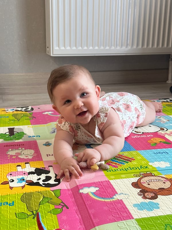 Baby on a cartoon play mat, smiling in Perm