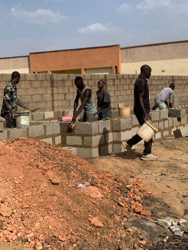 Construction workers build wall with concrete blocks in Nigeria