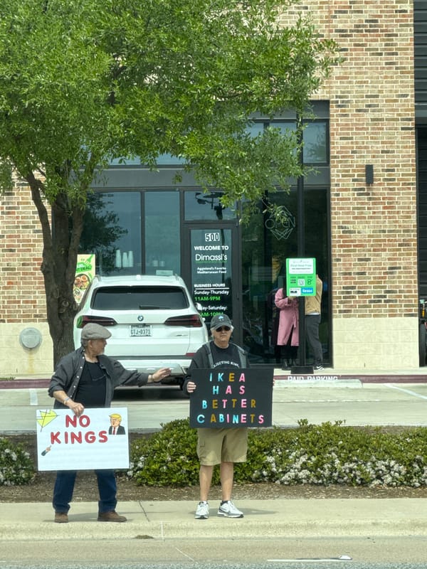 Two men hold protest signs on College Station sidewalk