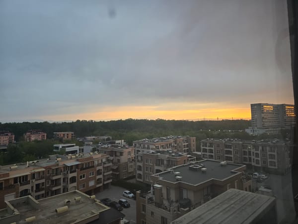 Sunrise or sunset observed over residential area through window