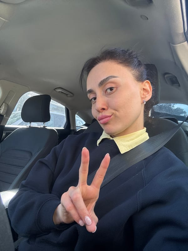 Woman poses for photos in car driver's seat in Tbilisi