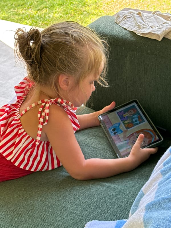 Child enjoys tablet time on outdoor furniture in Kuta