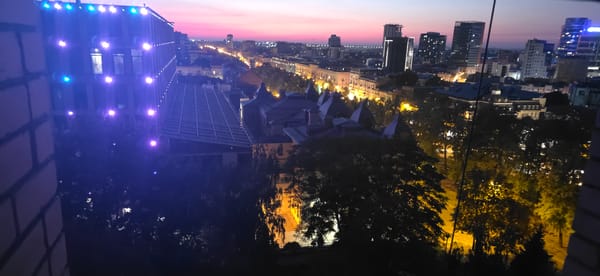 City skyline at dusk with a Ukrainian flag flying