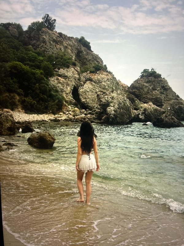 Woman in white dress stands in shallow beach water