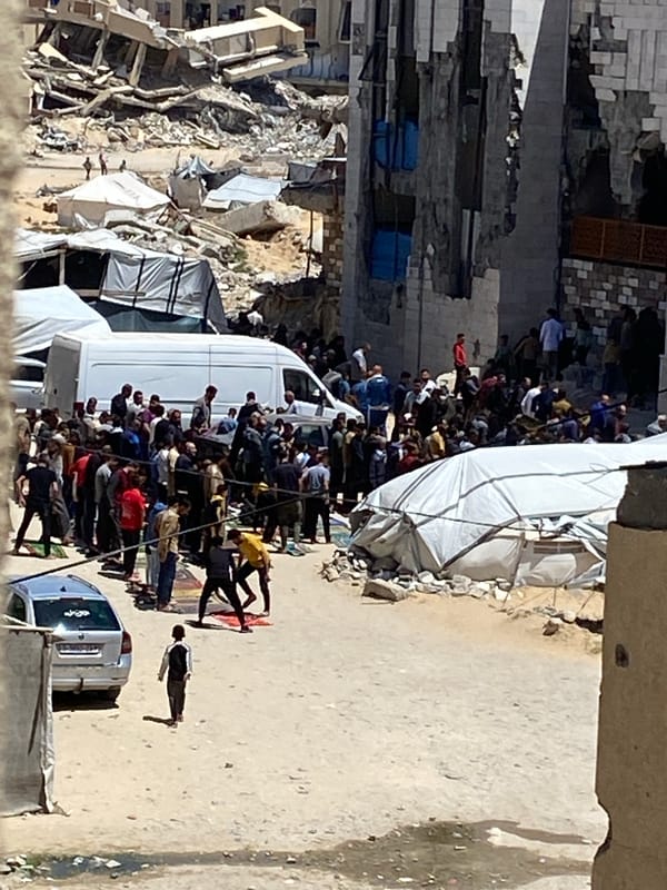 Large crowd gathers near damaged buildings in Khan Yunis