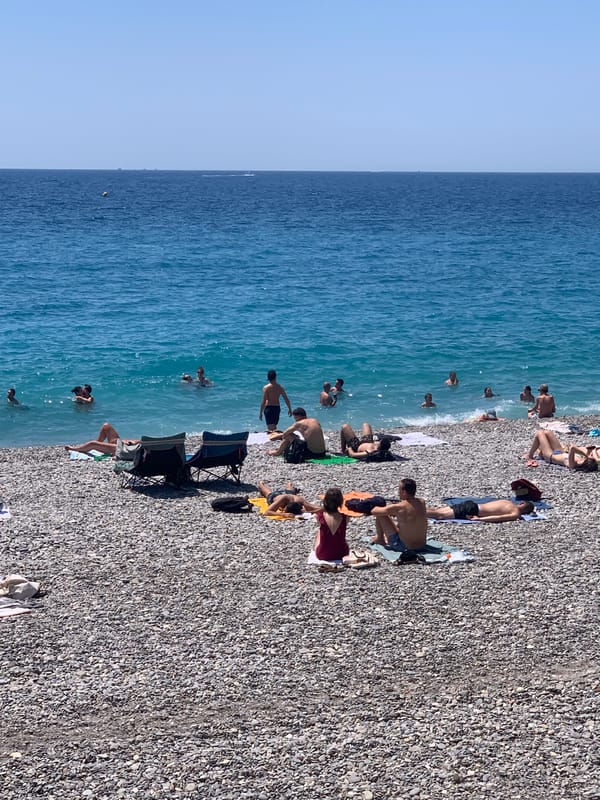 Packed summer day on Nice's pebble beach, Mediterranean in full swing