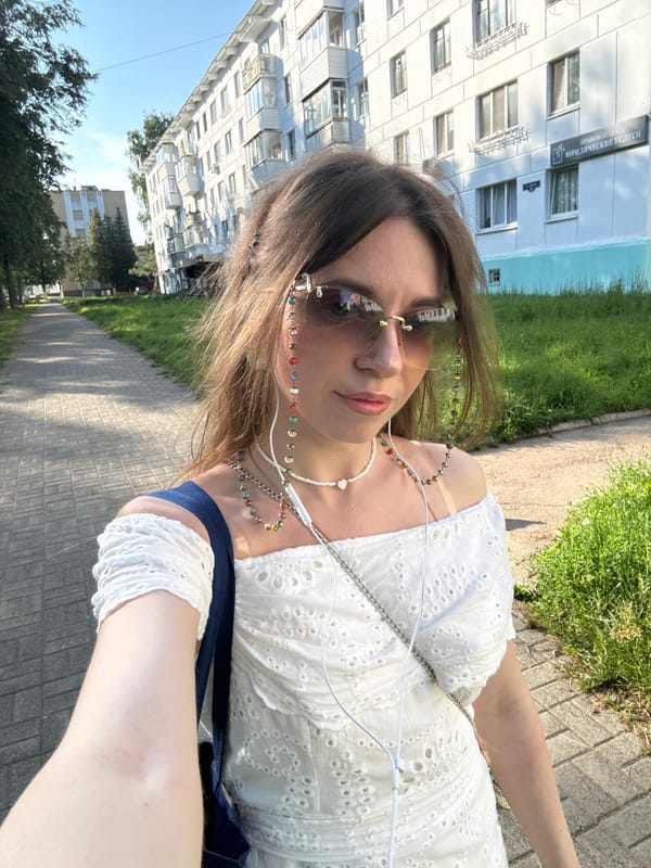 Strolling past apartments in a white dress and sunglasses