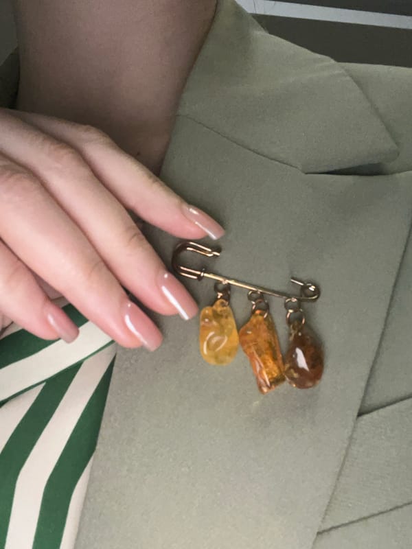 Person in green jacket with vintage brooch photographed in Podgorica