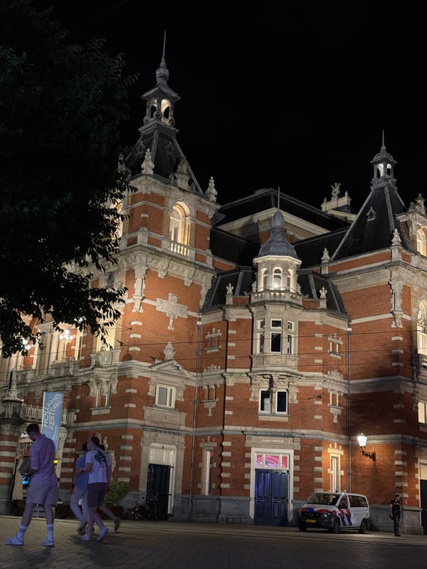 Police presence outside ornate Amsterdam building late at night
