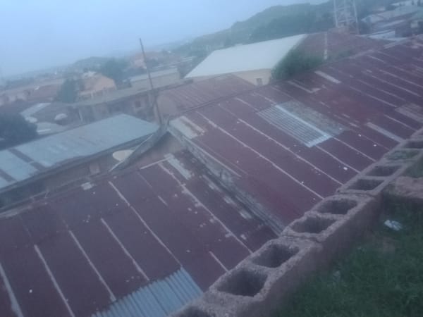 Aerial views show reddish-roofed urban settlement under overcast skies