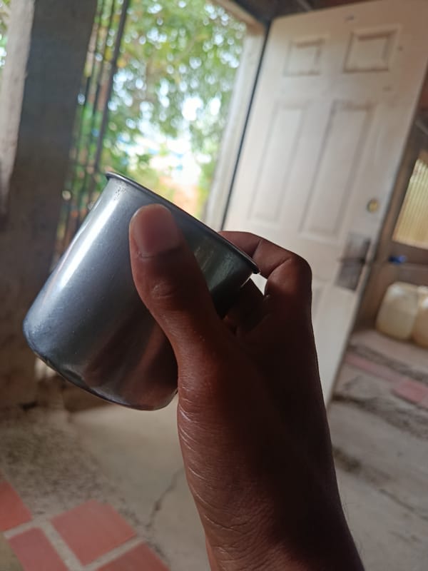 Metal cup with dark drink, doorway scene in Juan Griego