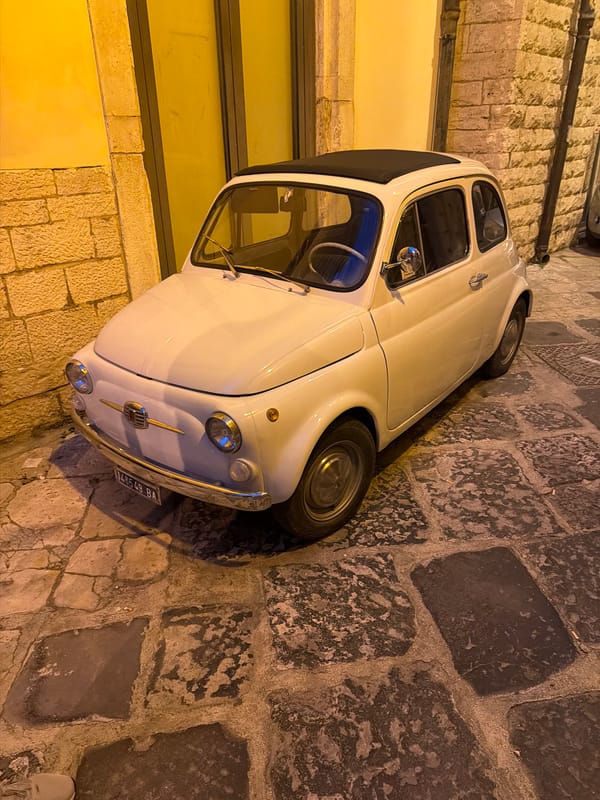 Pale yellow Fiat 500 parked on Bari's cobblestone streets