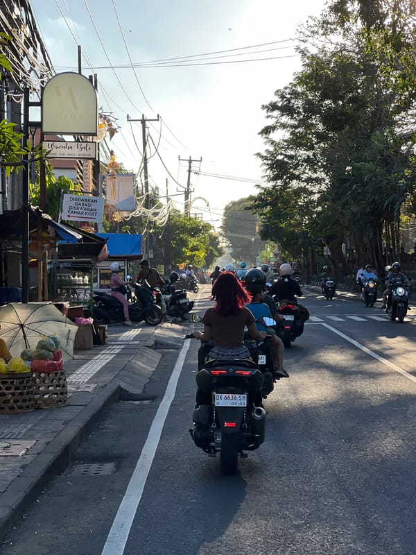 Motorcycle traffic flows through Denpasar streets at golden hour