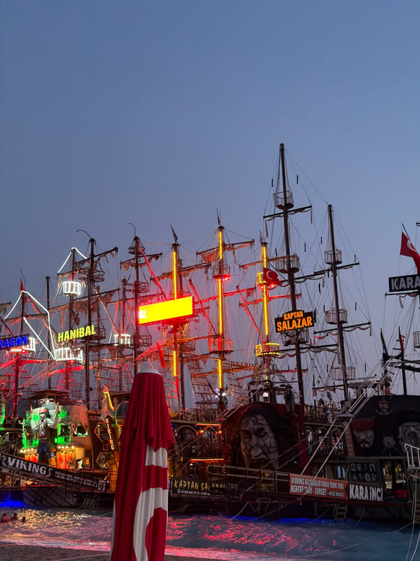 Neon-lit pirate boats line Fethiye harbor at dusk