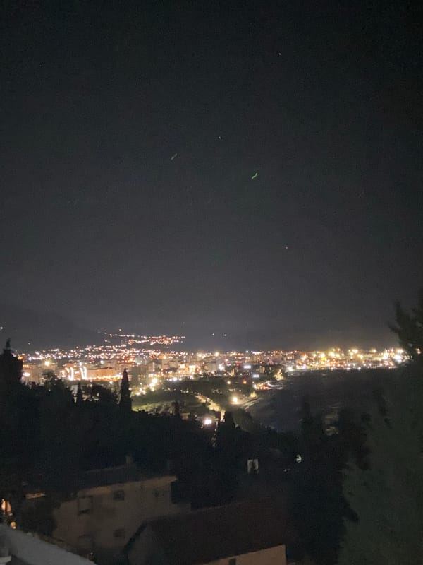 Nighttime coastal lights illuminate Šušanj, Montenegro from above