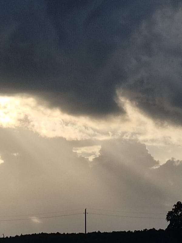 Storm clouds gather over a rural Lithuanian village at dusk