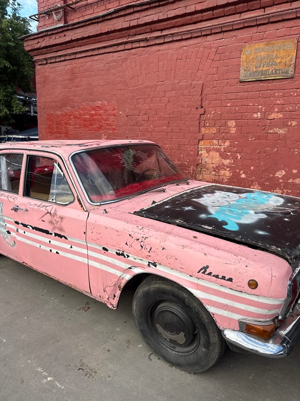 Worn Moscow streetscape: vintage cars, graffiti, and faded murals