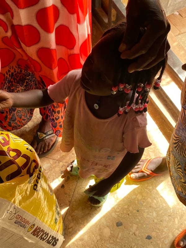 Child interacts with adults in busy Bukuru market area