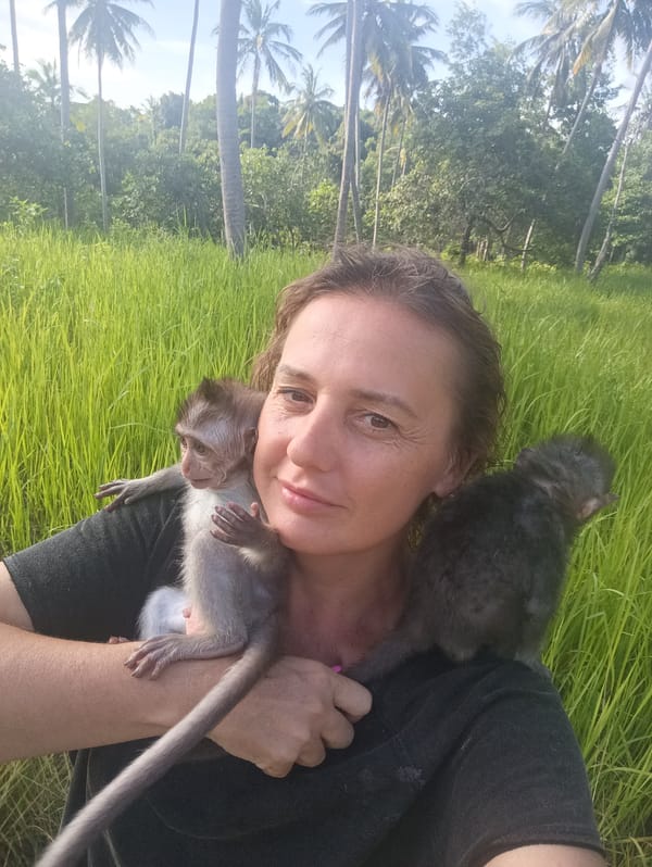 Woman holds baby monkeys in rural Thailand village