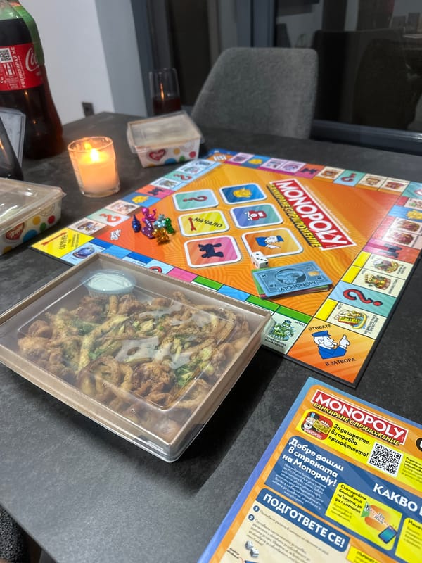 French bulldog plays while owner enjoys Monopoly and takeout