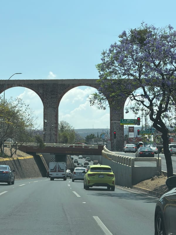 Stone aqueduct spans urban traffic scene