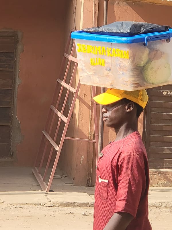 Man carries labeled food waste container in Maiburiji, Nigeria