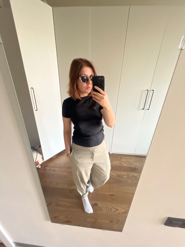 Mirror selfie in black tee, tan pants, and shades