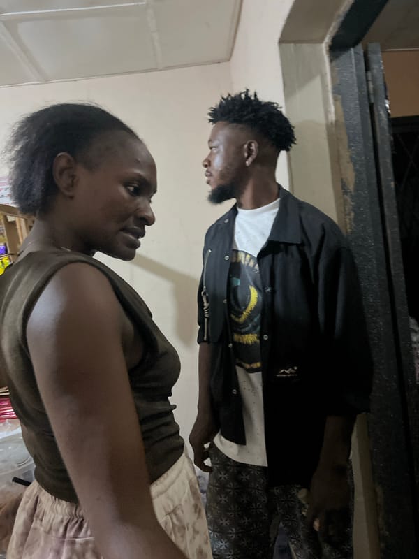 Two people in a dimly lit indoor space, Gura Top, Nigeria