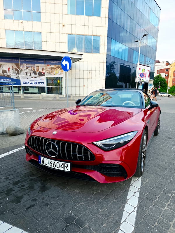 Glass office building and red Mercedes at sunset