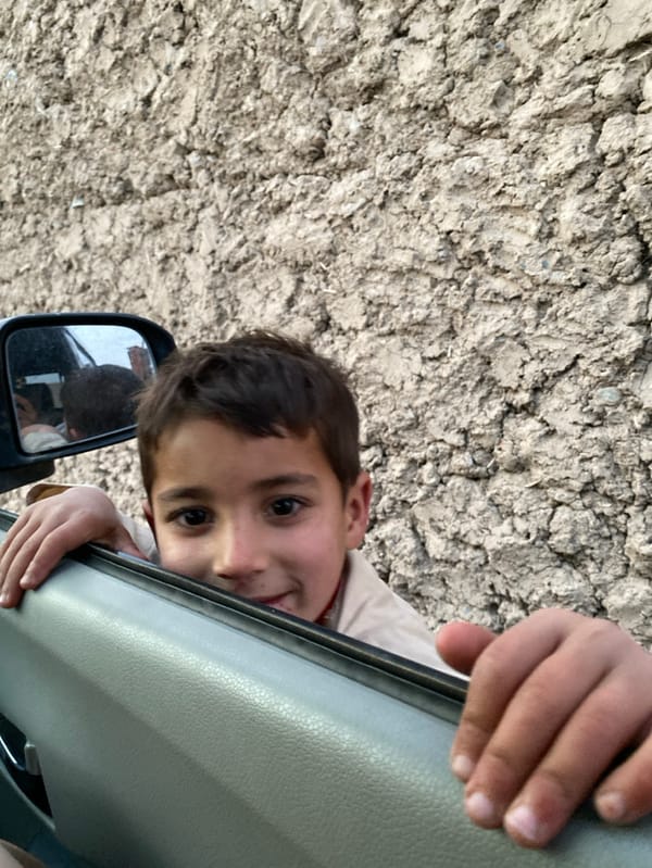 Young boy interacts with vehicle occupants in Kandahar
