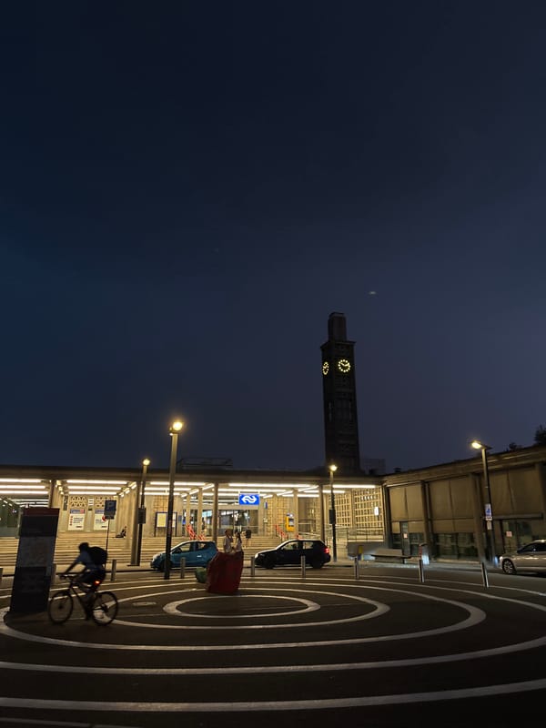Cyclist passes Enschede Central Station at dusk