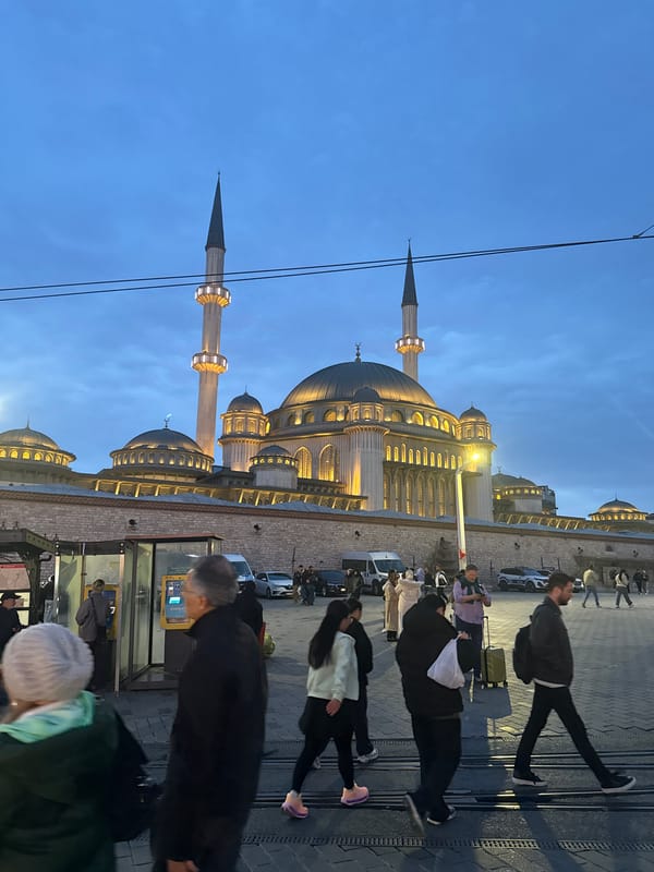 Evening pedestrians gather near illuminated mosques in Istanbul's Beyoğlu