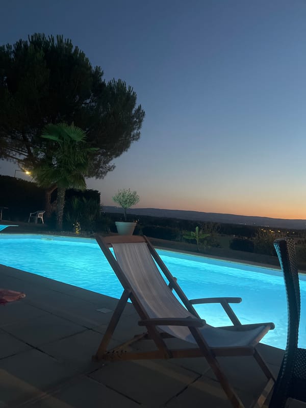 Evening poolside relaxation at a lit outdoor pool in Saint-Galmier