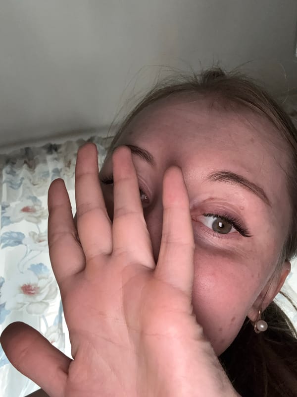 Person captured in angled portrait covering face with hand