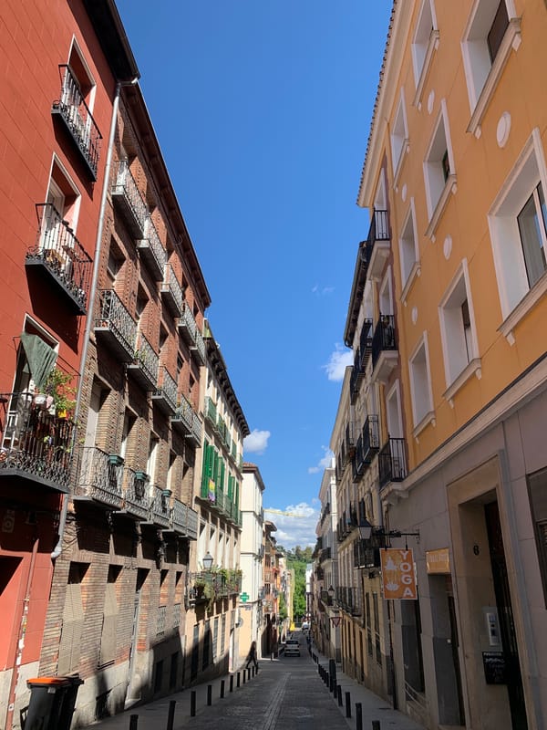 Woman walks narrow cobblestone street in Madrid