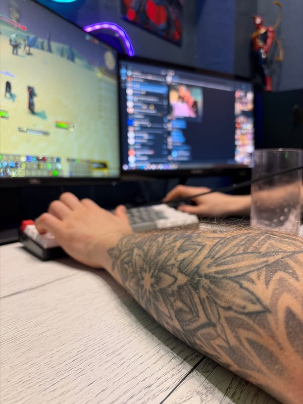 Tattooed person uses dual-monitor computer setup in Rostov-on-Don