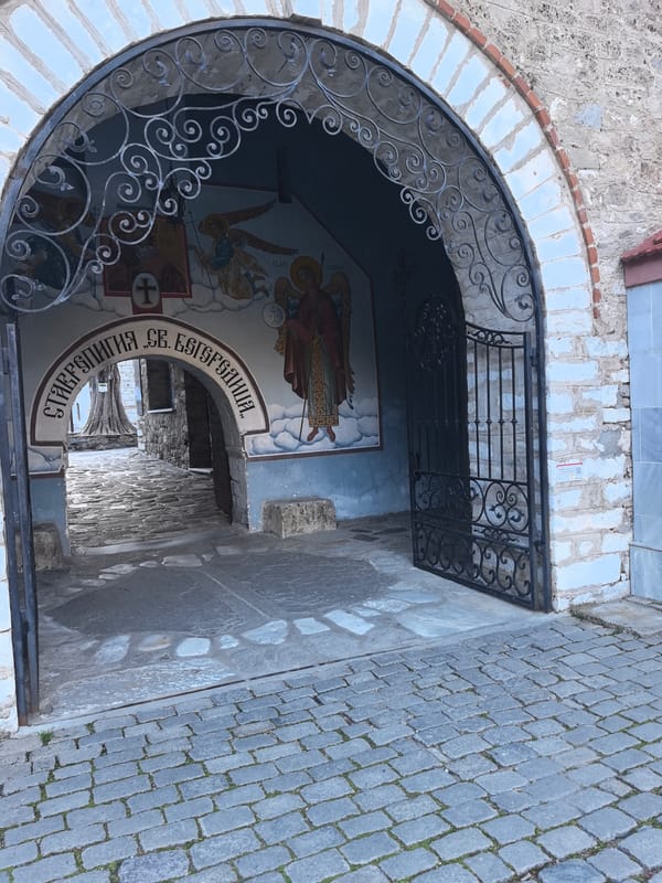 Ornate iron gate captured partially open at stone passageway