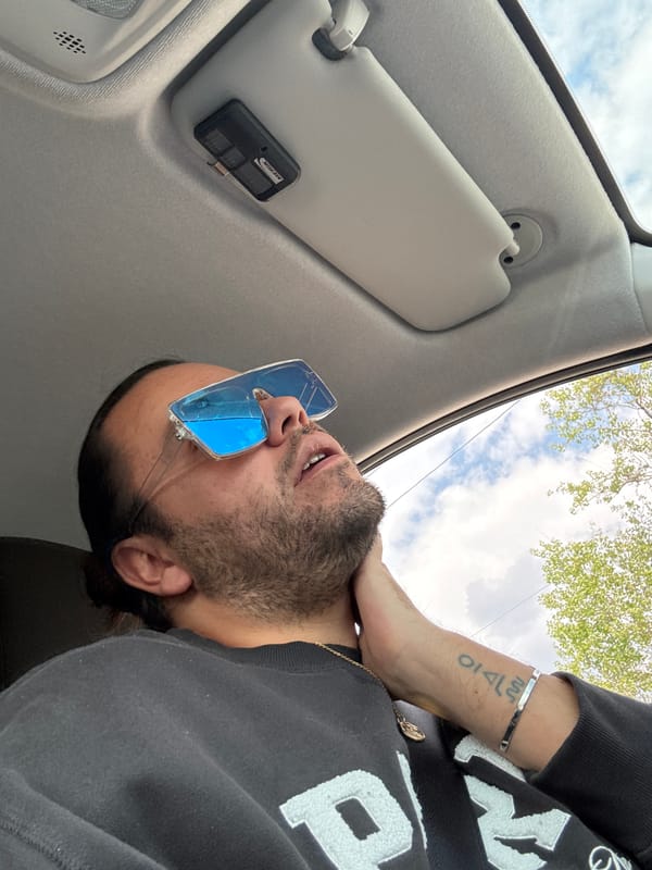 Man in blue sunglasses gazes skyward from car interior