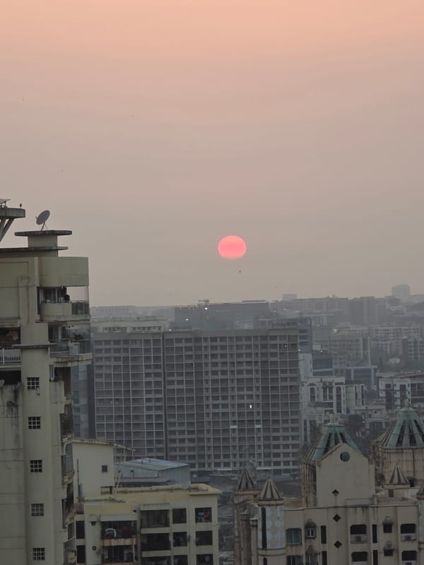 Vivid red-orange sun captured over Mumbai's hazy skyline