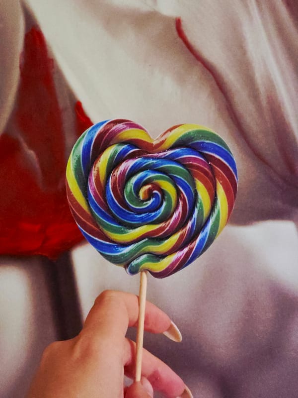 Heart-shaped rainbow lollipop photographed in garden settings