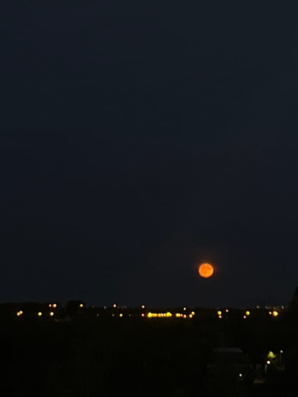 Orange moon rises over Samara as the Volga catches a summer sunset