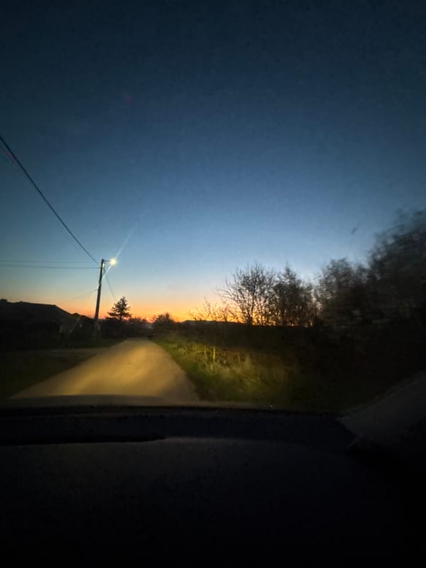 Vehicle passenger documents sunset to nighttime transition on rural road