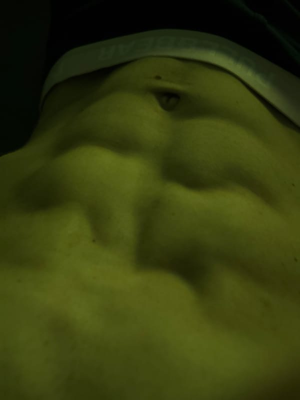 Close-up of defined abs in dramatic low-light setting