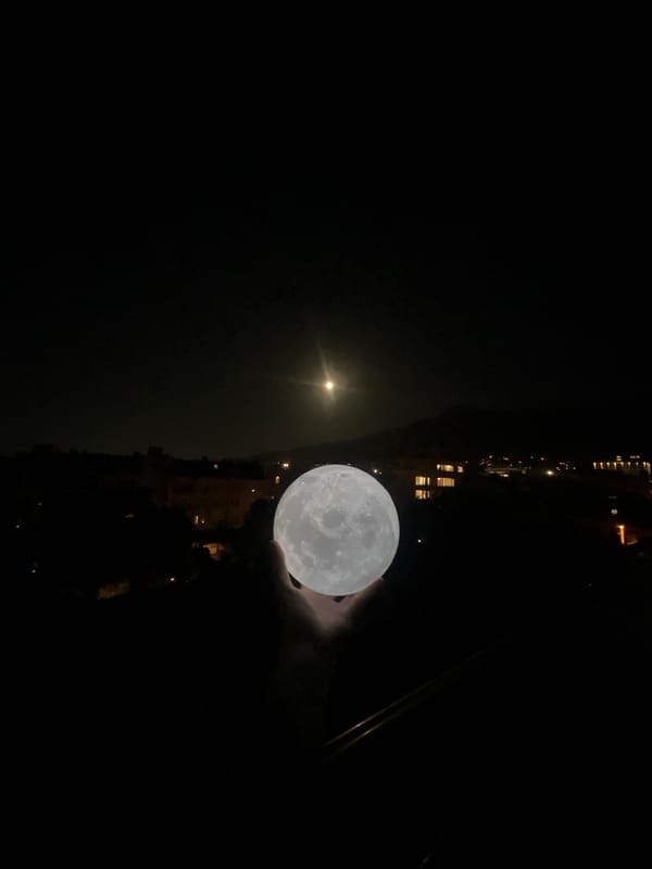 Person holds moon lamp beneath real moon in Sofia