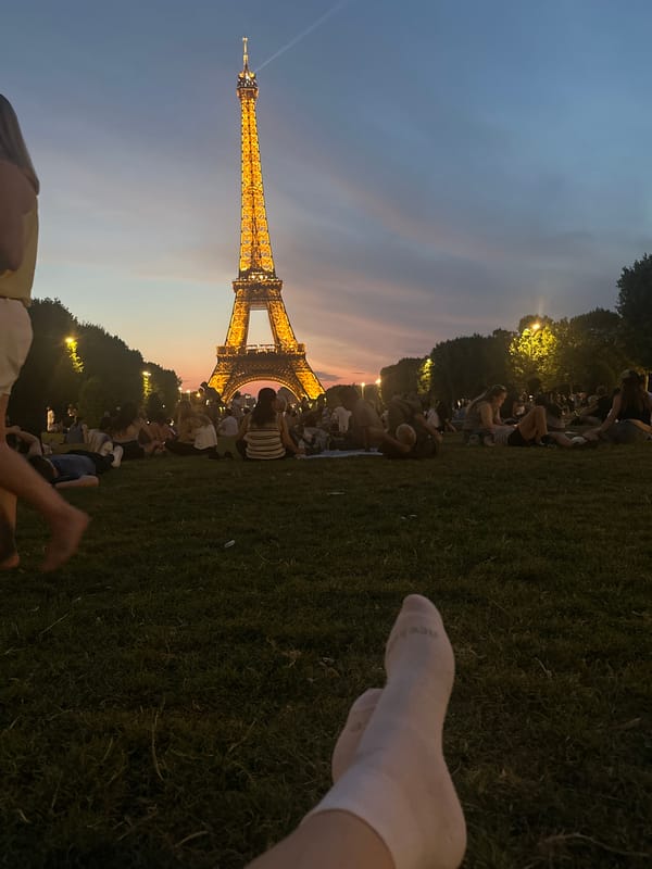 Eiffel Tower glows at dusk over a relaxed Champ de Mars crowd.