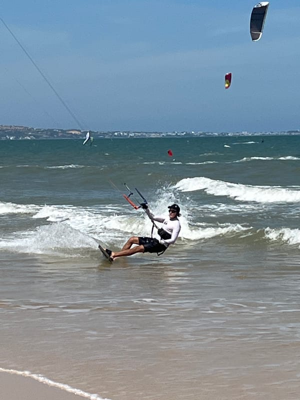 Kiteboarding off a sunny Vietnamese coastline on a choppy morning