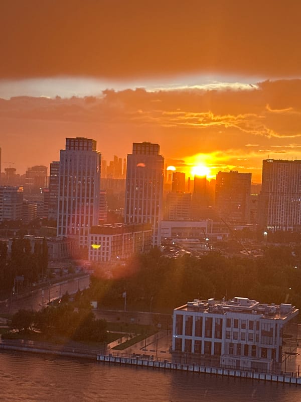 Moscow skyline glows at sunset, river and rooftops in frame